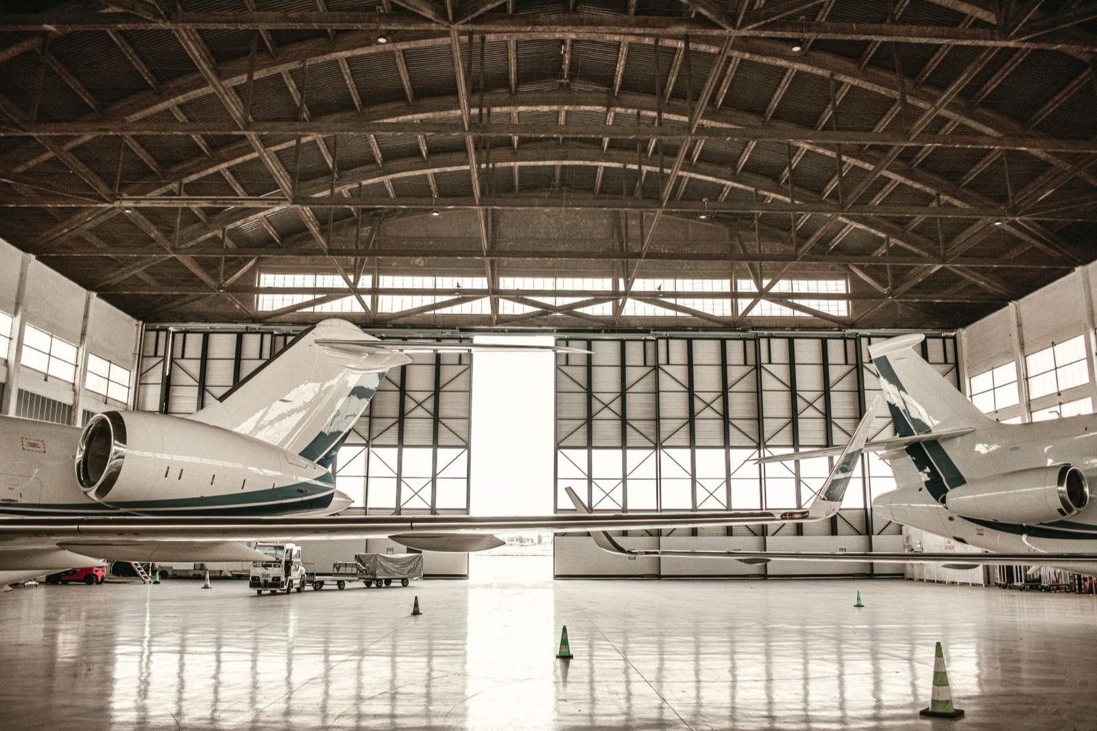 Two unmarked business jets facing each other inside an open hangar.